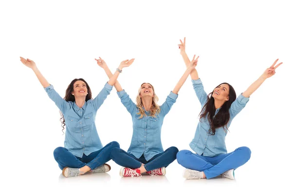 Mujeres haciendo la señal de victoria mientras están sentadas y miran hacia arriba — Foto de Stock