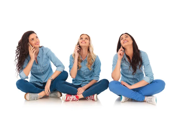 Tres mujeres casuales hablando por teléfono y mirar hacia arriba — Foto de Stock