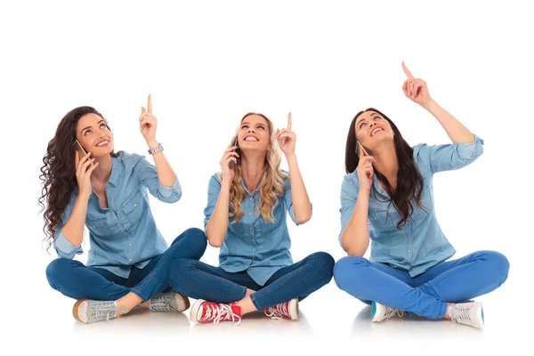 Três mulheres casuais falando ao telefone e apontando para cima — Fotografia de Stock