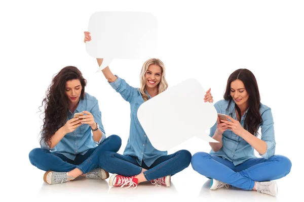 Zwei Frauen, die am Telefon SMS schreiben und eine hält Sprechblasen — Stockfoto
