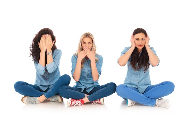 Три молодих жінки роблять ніяких злих позах сидячи — стокове фото
