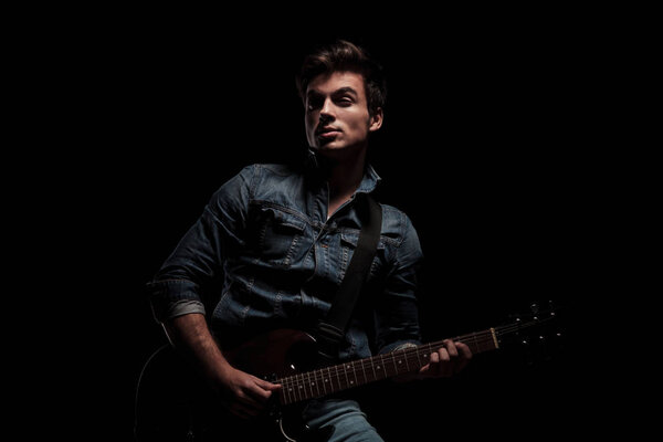 young man  playing electric guitar and looks to side