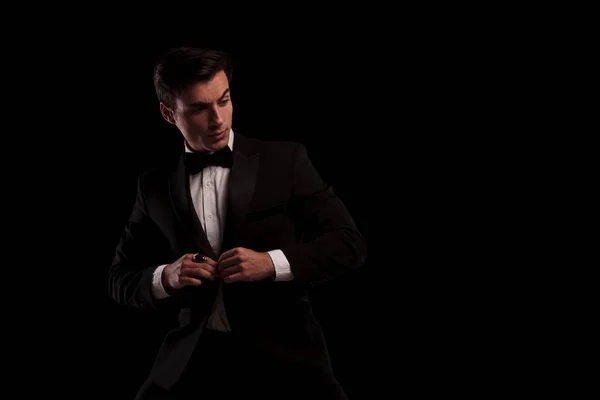 Homem elegante abotoando seu smoking e olha para o lado — Fotografia de Stock