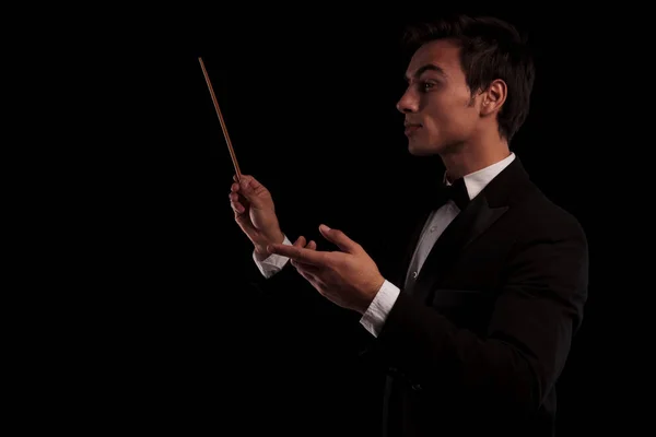 Vista laterale di un elegante direttore d'orchestra che tiene una battuta — Foto Stock