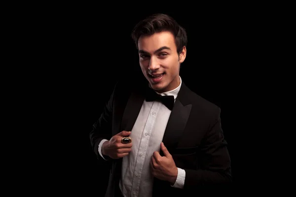 Excited young man wearing tuxedo and holding his collar — Stock Photo, Image