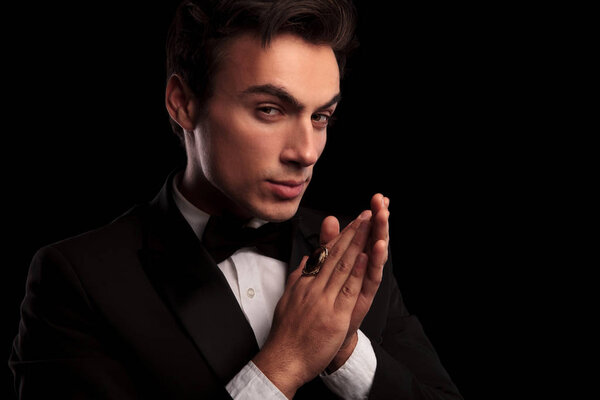 elegant man in tuxedo wearing big ring rubbing his palms