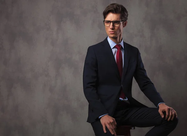 Modern young business man wearing glasses and sits on stool — Stock Photo, Image