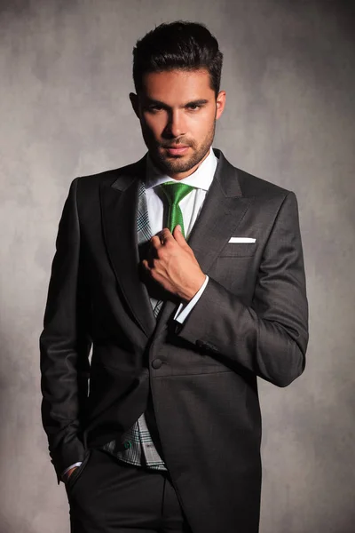 Young man in tuxedo coat fixing his green tie — Stock Photo, Image