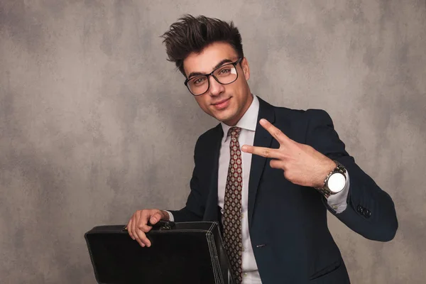 Business man holding briefcase and making the victory sign — Stock Photo, Image