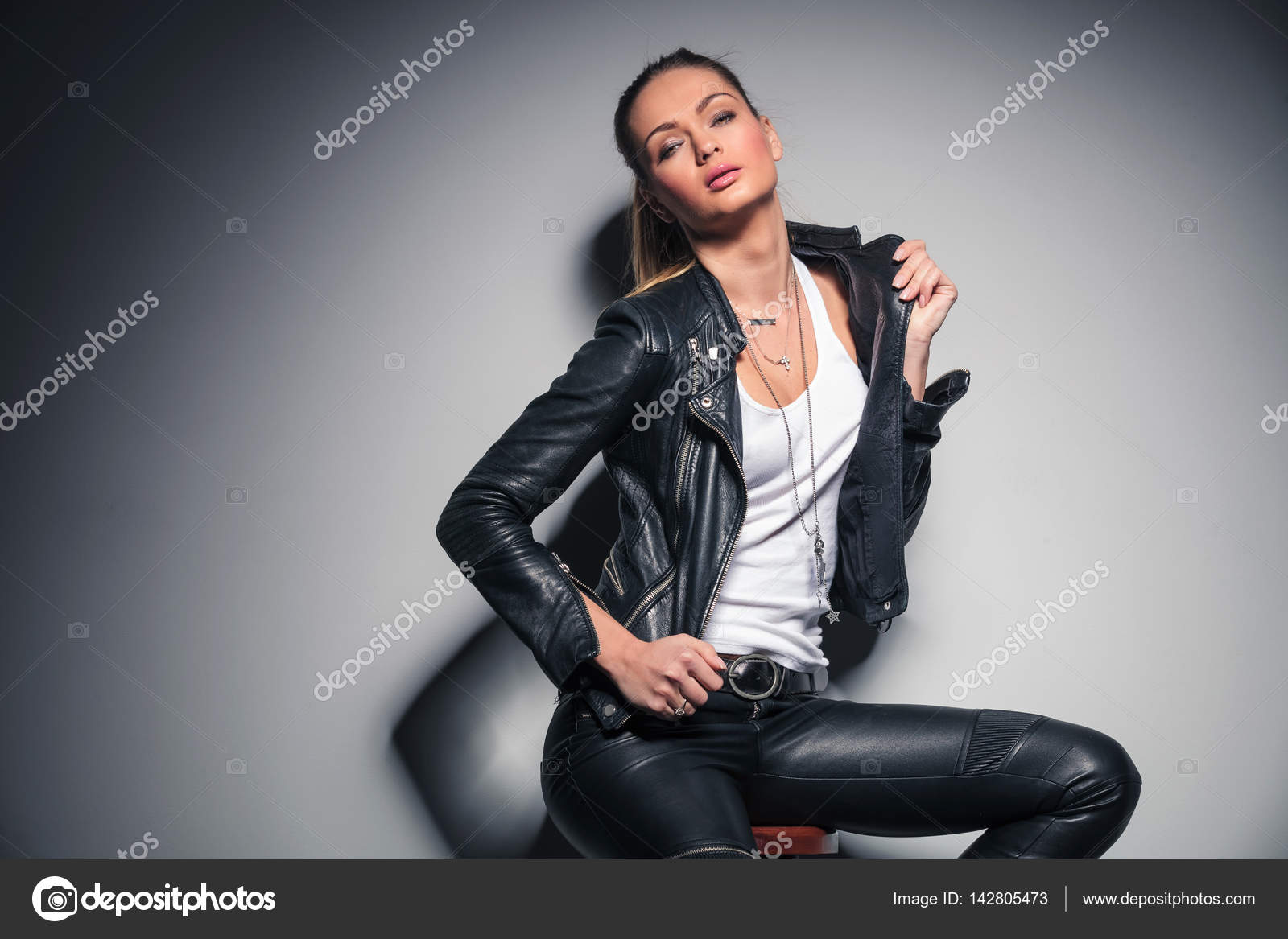 Attractive blonde woman in leather clothes sitting and posing Stock ...