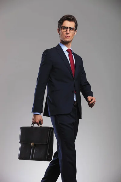 Pěší obchodní muž držící kufr a vypadá daleko — Stock fotografie