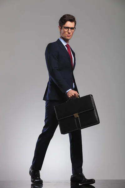 Negocios serios sosteniendo un maletín camina hacia adelante con confianza —  Fotos de Stock