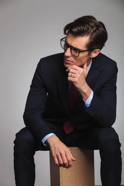 Nachdenklicher junger Geschäftsmann sitzt und blickt zur Seite — Stockfoto