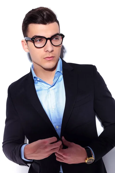 Young man unbuttoning his coat while looking away — Stock Photo, Image