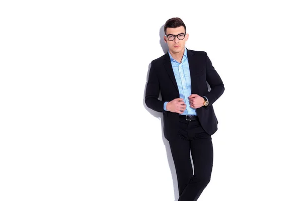 Elegant young man wearing glasses and suit holding collar — Stock Photo, Image