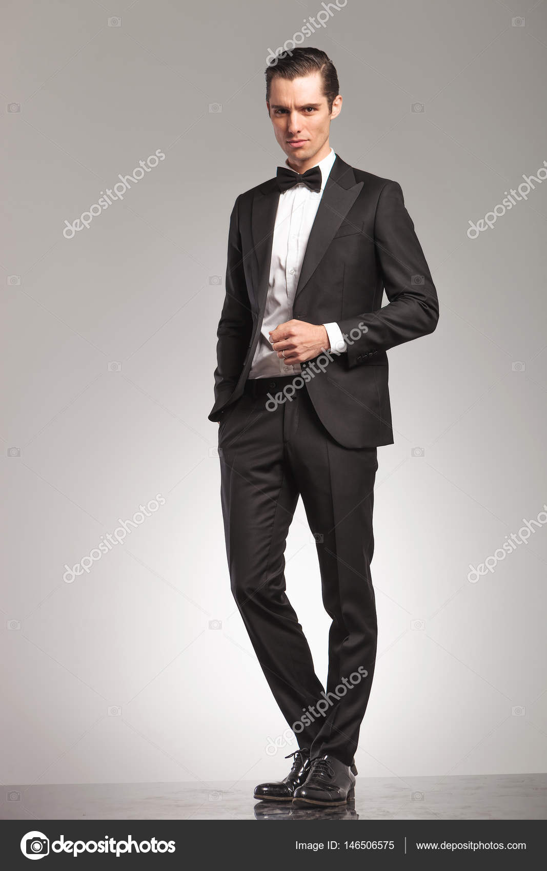 Elegante hombre de negocios en esmoquin de pie con abrigo abierto