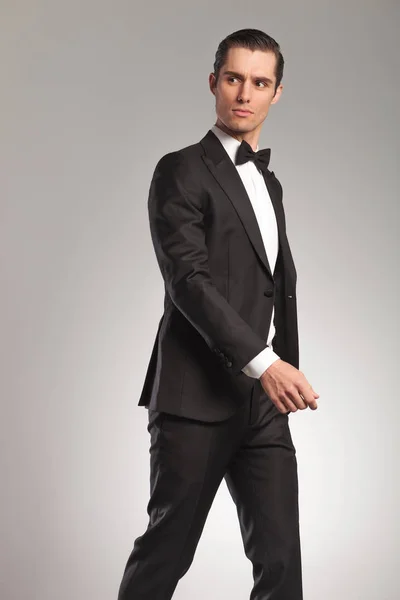 Wandelen van de elegante jongeman in tuxedo op zoek naar kant — Stockfoto