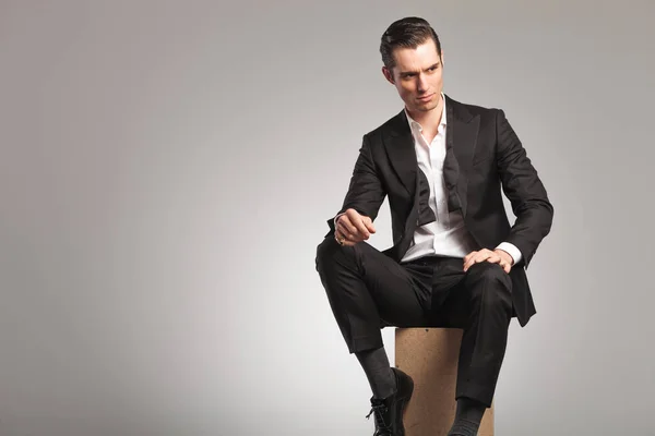 Seated man in tuxedo and undone bowtie looks  to side — Stock Photo, Image