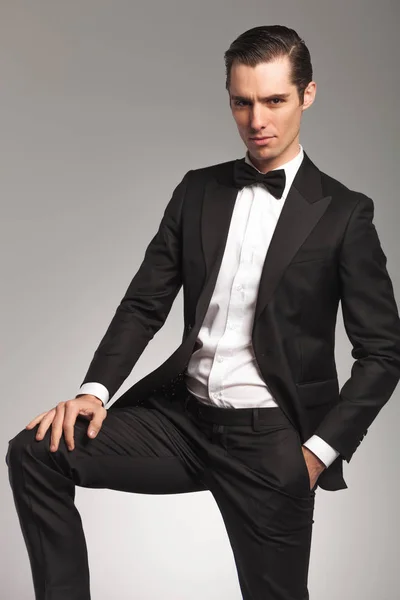 Elegant man med handen på knät och en i ficka — Stockfoto
