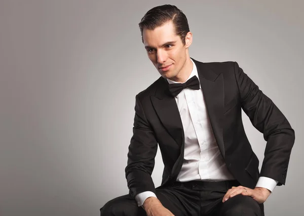 Side view of a smiling seated young man in tuxedo — Stock Photo, Image