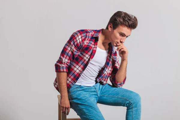 Sidovy över en omtänksam ung casual man sittande — Stockfoto