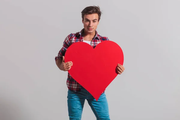 Fajny młody człowiek posiadający duże czerwone serce — Zdjęcie stockowe