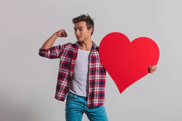Mann lässt seine Muskeln spielen und hält ein großes rotes Herz — Stockfoto