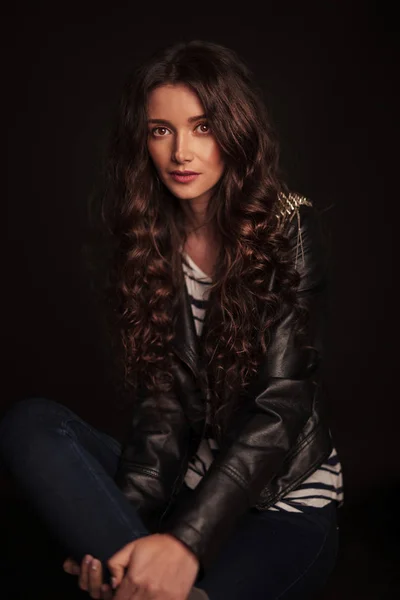 Portrait d'une jeune femme décontractée en veste en cuir assise — Photo