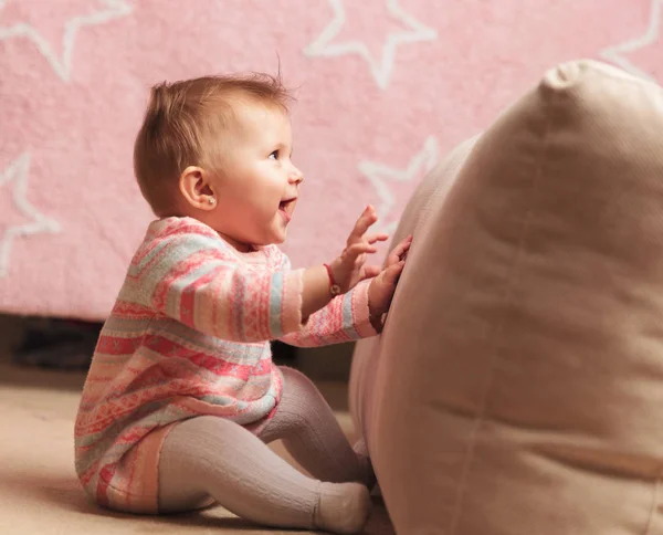Assise bébé fille s'amuser avec oreiller et regarde vers le haut — Photo
