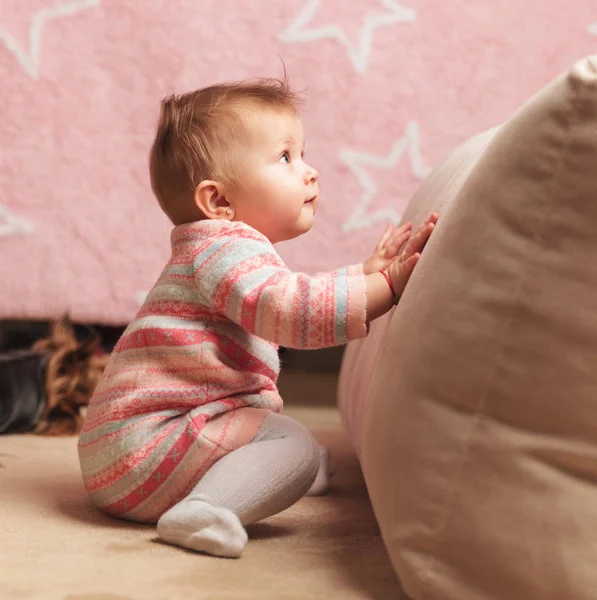 Bonito bebê menina empurrando um travesseiro e olha para cima — Fotografia de Stock