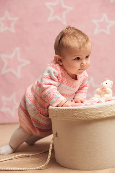 Schattige babymeisje haar zelf omhoog te trekken op een doos — Stockfoto