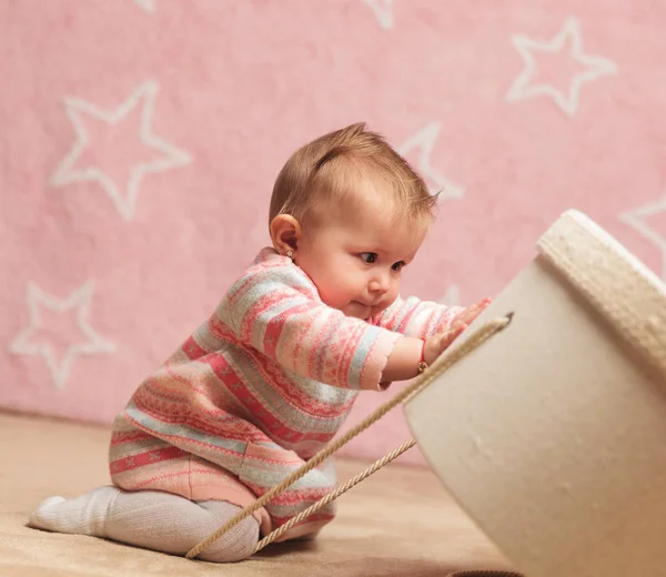 Vista lateral de una linda bebé niña empujando caja —  Fotos de Stock