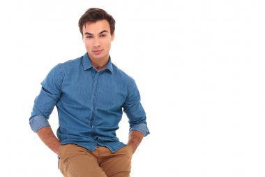 Elleri ceplerinde oturan genç casual adam 