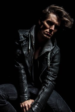 deri ceketli rahat dramatik adamı oturur ve uzak görünüyor