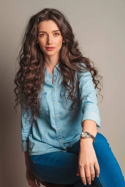 Femme souriante avec les cheveux bouclés assis sur la chaise — Photo