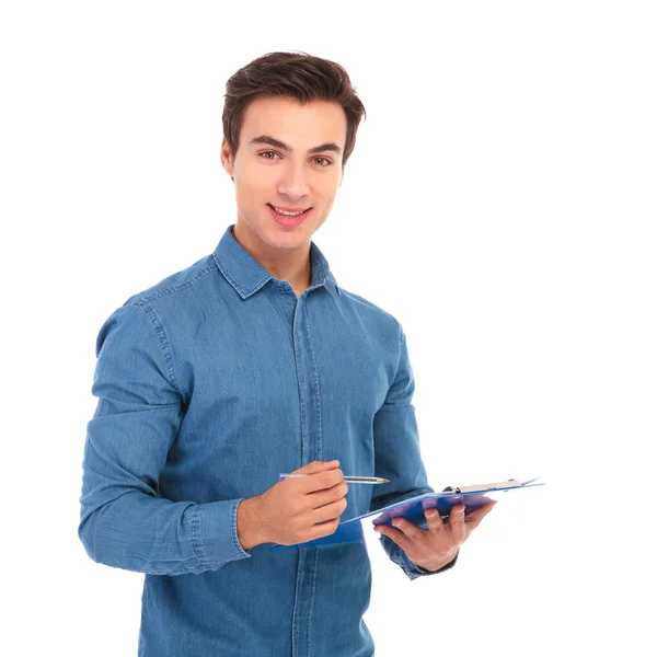 Sonriente hombre casual escribe en portapapeles — Foto de Stock