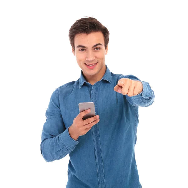 Jovem casual homem segurando telefone e apontando dedo — Fotografia de Stock