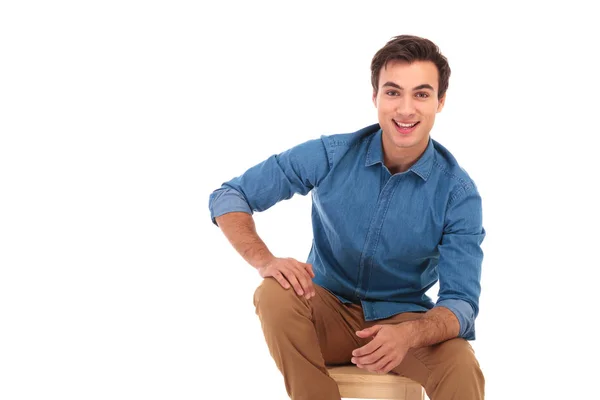 Atraktivní ležérní mladík s úsměvem a sedí — Stock fotografie
