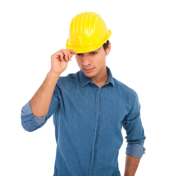 Молодий інженер-будівельник тримає свій шолом безпеки і дивиться — стокове фото