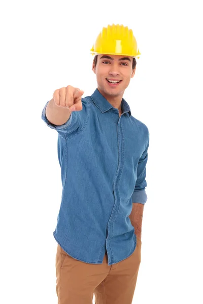 Молодой инженер в жёлтом шлеме, указывающий пальцем — стоковое фото