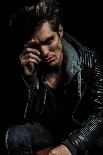 fashion model with hand on his face looking pensive