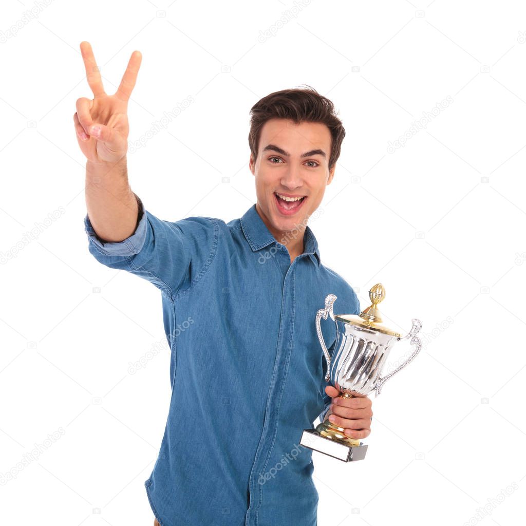 surprised  man winning  cup award and makes the victory sign