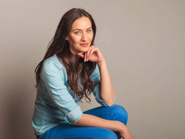 Souriant femme décontractée dans la pensée et assis sur la chaise — Photo