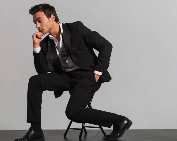 Vista laterale di un uomo elegante e premuroso seduto sulla sedia — Foto Stock