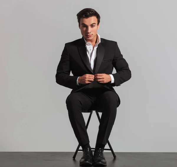 Sitzender eleganter Mann knöpft sich seinen Anzug zu — Stockfoto