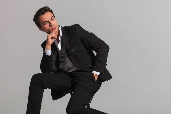 Sitzendes Mode-Model im Smoking blickt über seine Schulter — Stockfoto