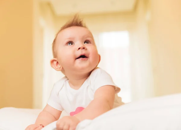 Pequena menina sentada em sua cama está sonhando longe — Fotografia de Stock