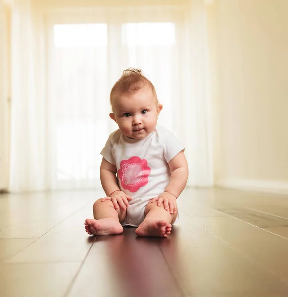 Sérieux bébé fille assis sur le sol — Photo