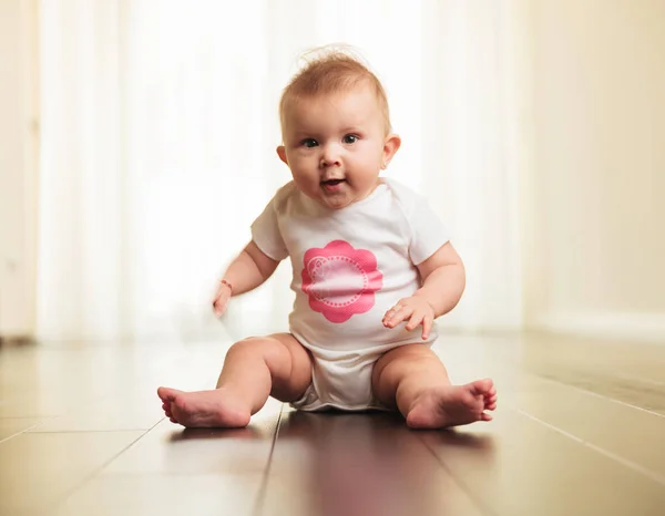 Ansiosa pequena menina sentada no chão de madeira — Fotografia de Stock