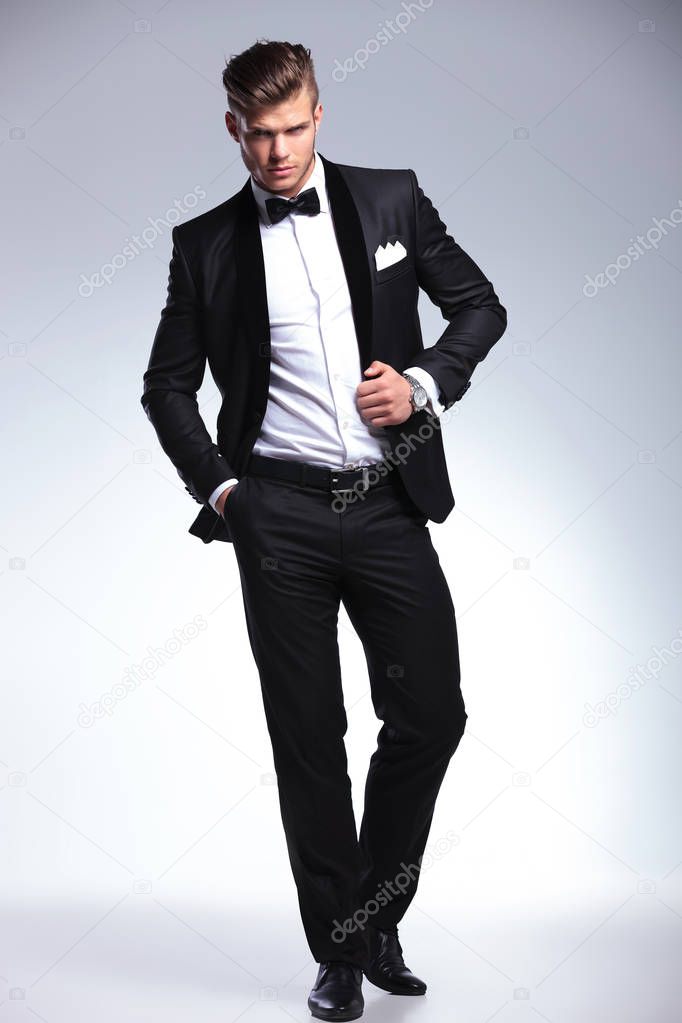 tuxedo man poses with hand on jacket and in pocket